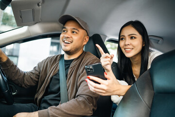 Young asian woman traveler talking with taxi driver explain the route how to travel in direction destination. Passenger showing the direction to taxi driver travel in city. Driver application service