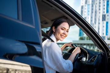 Young beautiful asian business women getting new car. She very happy and excited. Smiling female driving vehicle on the road on a bright day with sun light. Business woman buying driving new car