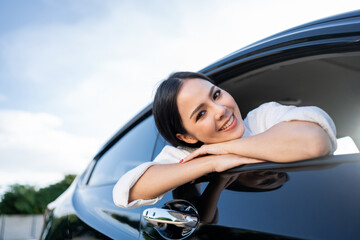 Young beautiful asian business women getting new car. Happy smiling female driving vehicle on the road Sticking her head outta the windshield with sun light. Business woman buying driving new car