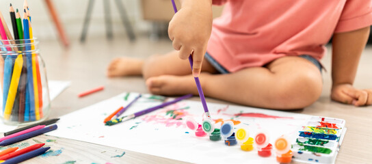 Happy moment little cute girl creating and water color painting activity with paint brushes on...