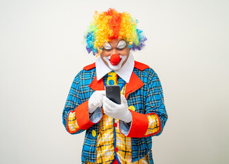 Mr Clown. Portrait of Funny face Clown man in colorful uniform standing holding smartphone. Happy expression male bozo in various pose with cellphone on isolated background.