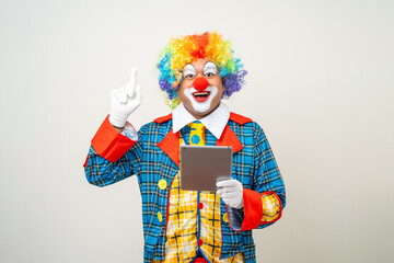 Mr Clown. Portrait of Funny face Clown man in colorful uniform standing holding tablet. Happy expression male bozo in various pose with laptop on isolated background.