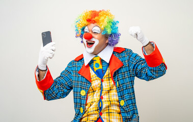 Mr Clown. Portrait of Funny face Clown man in colorful uniform standing holding smartphone. Happy...