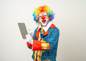 Mr Clown. Portrait of Funny face Clown man in colorful uniform standing holding tablet. Happy expression male bozo in various pose with laptop on isolated background.