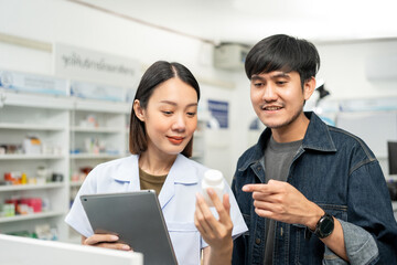 Pharmacist recommends medicines to customers.Taking the questions of medication. Asian female pharmacist giving prescription medications to customers at drugstore shelves.