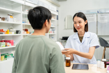 Fototapeta premium Pharmacist recommends medicines to customers.Taking the questions of medication. Asian female pharmacist giving prescription medications to customers at drugstore shelves.