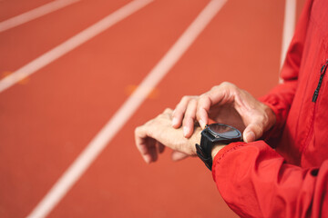 Young man wearing sportswear red jacket using Smart Watch Showing Heart Rate Monitor. Technology...