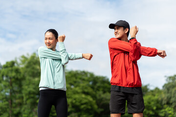 Couple asian jogging and running outdoors at sport stadium warming up stretching before workout....