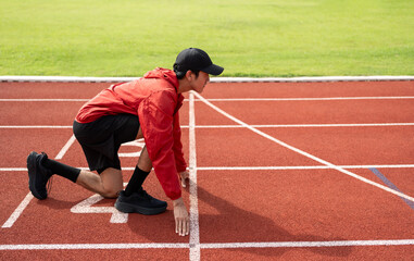 Young handsome indian man doing start pose before running exercise on track in sport stadium....