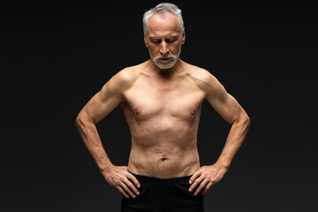 Fototapeta na wymiar Senior retired man with gray hair shirtless with closed eyes standing isolated on black background