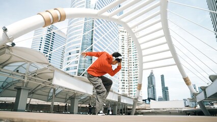 Asian hipster wearing headphone show footstep while jumping at city. Professional break dancer perform b-boy dancing performance at city. Break dance or street dance. Outdoor sport 2024. Sprightly.