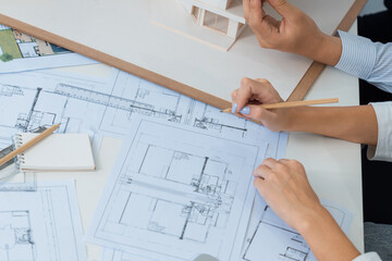 Top view image of professional beautiful young architect hand drafts blueprint while asian...