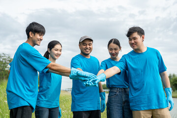 Happy volunteer people group charity with garbage bags cleaning up in park. Corporate social...