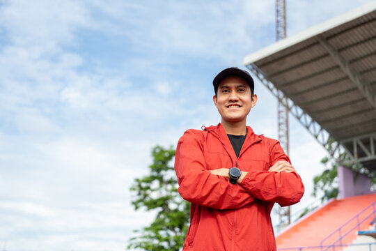 Young handsome asian man wearing sportswear standing post on running track at sport stadium outdoor. Portraits of Indian man jogging on the road. Training athlete outdoor concept.