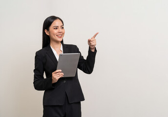 Attractive elegant young asian business woman using digital tablet standing on isolated background. Happy young latin female formal black suit holding tablet gadget working service with customer