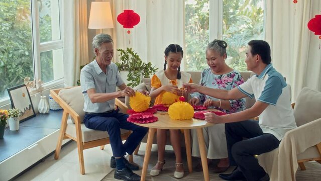 Wide shot of multi-generational family preparing decorations for Tet celebration at homeWide shot of multi-generational family preparing decorations for Tet celebration at homeWide shot of multi-gener
