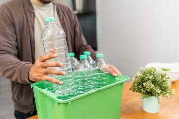 A young man arranged plastic bottles into a box. He assumes plastic bottles will sort of trash...