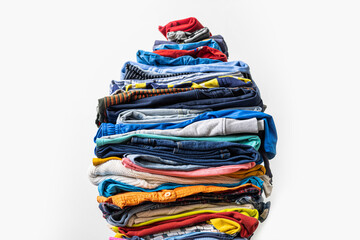 A very tall stack of folded colored clothes for charity, washing, ironing and sorting.