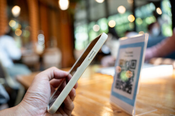 Woman use smartphone to scan QR code for order menu in cafe restaurant with a digital delivery....