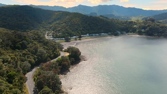 Aerial: Coastline road, beach and hills in Oamaru Bay, Coromandel Peninsula, New Zealand.