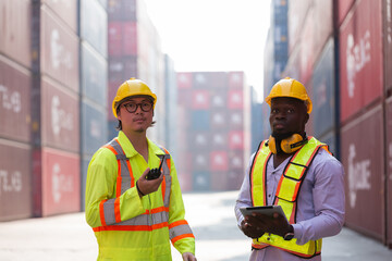 Group of male container yard worker loading containers box with digital tablet at commercial dock site. Team of container worker checking container at container terminal yard