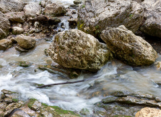 Naklejka na ściany i meble Morning on a mountain river, the unhurried flow of a stream among a stone bed.