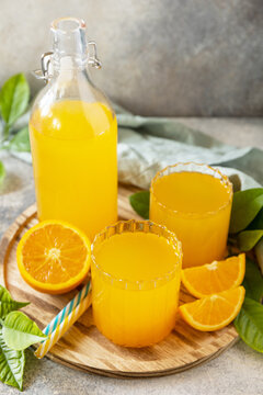 Ripe oranges and two glasses of fresh juice squeezed orange juice on a stone tabletop. Copy space.