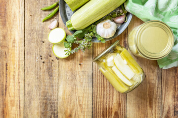 Healthy homemade fermented food. Pickled zucchini with mint preserved canned in glass jar. Home economics, autumn harvest preservation. View from above. Copy space.