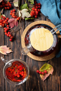 Autumn tea, berry vitamin seasonal drink. Viburnum and cup of healthy viburnum tea on a wood background. View from above.