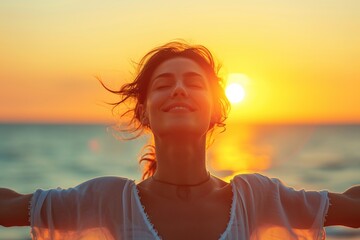 Happy woman with open arms and closed eyes on the seashore at sunset.