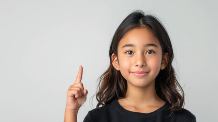 Beautiful Asian girl, pointing finger up at copy space isolated on background.