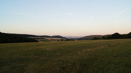 grass and wildflowers stand mowed in the fields in the evening rays before sunset