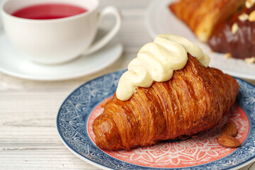 Fresh croissants with cup of tea on table