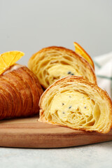 Glazed croissant with dried orange on wooden board