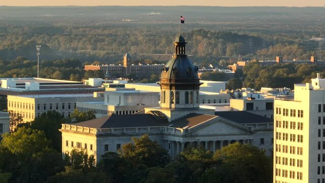 Dawn light on the South Carolina State House dome with the flag above. Aerial parallax during sunrise.