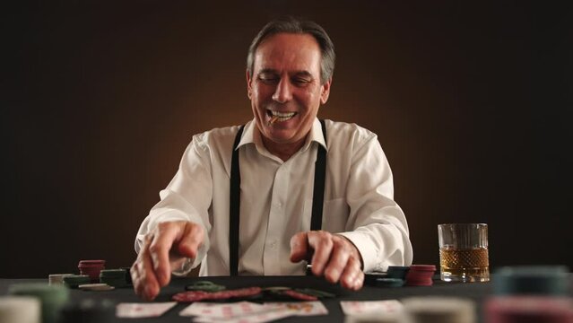 A man in high spirits collects all the poker chips after revealing a winning hand, with a cigarette in hand, savoring his victory at the table. Camera 8K RAW. 