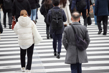 冬の都市の交差点の横断歩道を渡る人々の姿