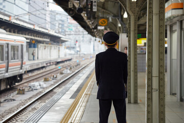 冬の名古屋駅のホームで電車待ちの駅係員の姿