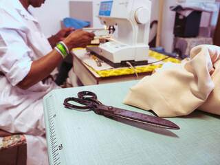 close up of adult black seamstress use sewing machine to skillfully sew a shirt with precision care