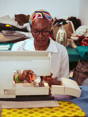 close up of adult black seamstress use sewing machine to skillfully sew a shirt with precision care