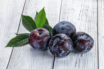 Raw purple plums heap with leaves