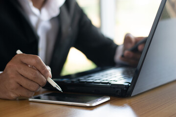Businessmen or accountants work on computers and write down business documents on their desks.
