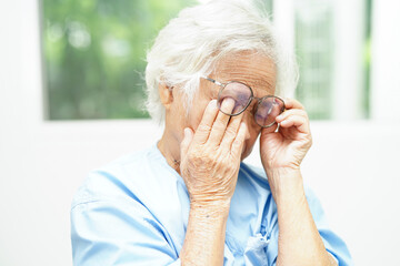 Asian senior woman wearing eyeglasses reduce headache and eyestrain suffer at home care service.