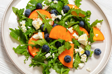 arugula persimmon cheese berries salad, top view