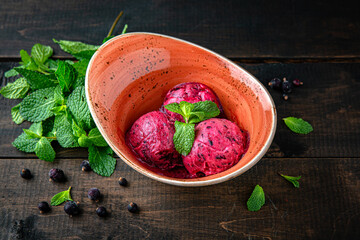 Ice cream berry sorbet made from blackcurrant and mint. Menu for a restaurant. Beautiful composition on wooden boards. - obrazy, fototapety, plakaty
