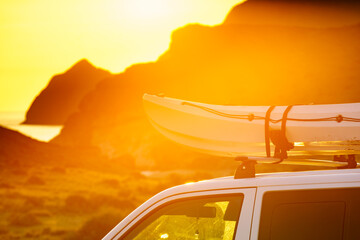 Canoe on roof top of car van at sunset