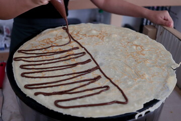 Crepe and chocolate cream line grilling on hot plate.