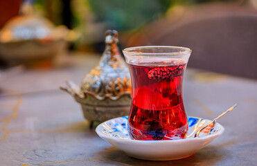 Traditional tulip shaped glass of Turkish mulberry tea or chai, lokum Turkish delight candy served...