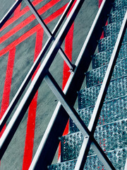 Abstract urban texture with contrasting red lines and metal stairs on a gray background.