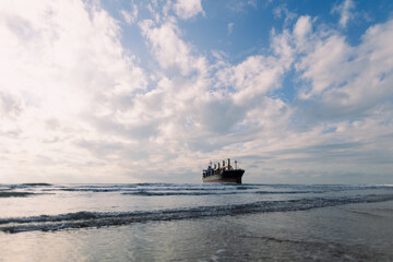 A large cargo sea ship sails on the ocean among the waves